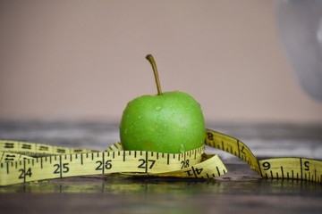 Measuring tape wrapped around a green apple. Concept symbol of diet.