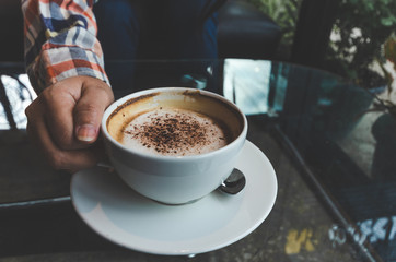 closeup woman drinking modern hot black coffee the cappuccino on dark background with coffee bubble foam pattern and texture in black cup looking and feel so delicious on glasses table in coffee shop.