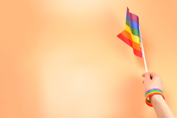 LGBT flag in woman hand on orange background. Copy space.
