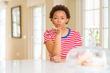 Young beautiful african american woman at home looking at the camera blowing a kiss with hand on air being lovely and sexy. Love expression.