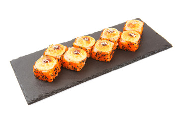 Baked hot sushi roll on a black stone plate on white background Healthy and tasty food.