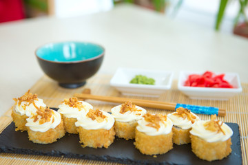 Japanese breakfast set tamagoyaki sushi roll with rice, cheese, salmon and avocado closeup on a plate on the table. vertical Healthy and tasty food.