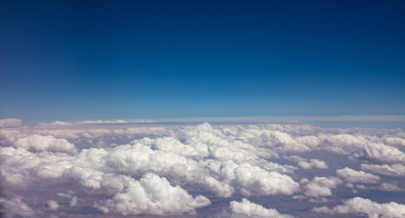 Fototapeta na wymiar Blue sky and fluffy clouds. View out of a plane window.