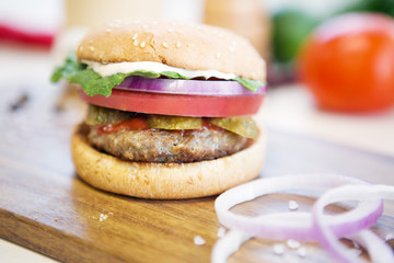 Delicious fast food. Home made hamburger with lettuce, cheese, beef meat and french fries placed on old wooden table