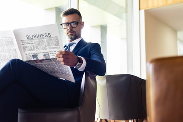 handsome businessman in suit and glasses reading newspaper business