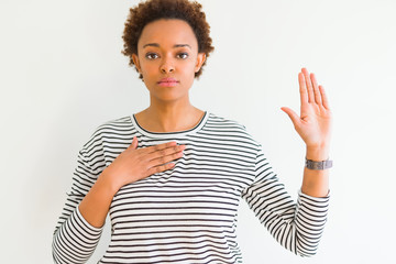 Young beautiful african american woman wearing stripes sweater over white background Swearing with...