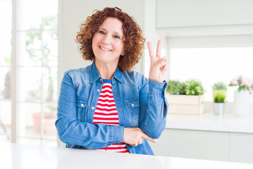 Middle age senior woman with curly hair wearing denim jacket at home smiling with happy face...
