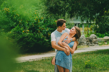 Beautiful couple in bright clothes walks in a summer park in the city. Walk in the fresh air. Date of two lovers. The period of courtship of a man for a woman, romantic meetings in nature