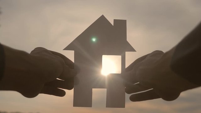 happy family house construction concept. man holding home a paper house in his hands at sunset silhouette sunlight. life ecology video symbol lifestyle