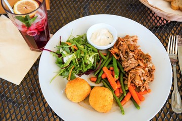 Table with main dish (pork,croquettes,salad) and lemonade.