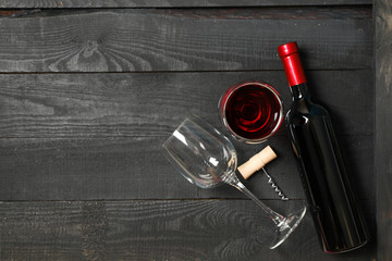 Flat lay composition with bottle of wine, glasses and corkscrew on wooden background, copy space