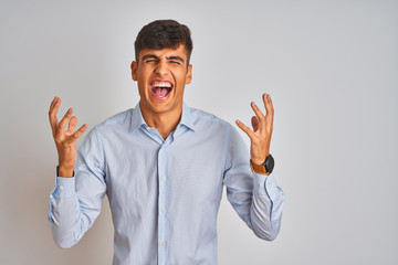 Young indian businessman wearing elegant shirt standing over isolated white background celebrating mad and crazy for success with arms raised and closed eyes screaming excited. Winner concept