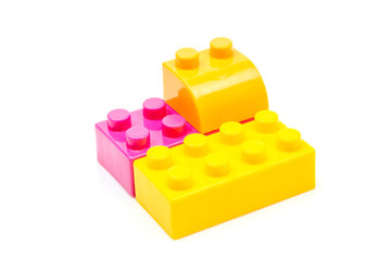 Fototapeta premium Pink and yellow plastic building block isolated on white background. Developmental toys for children.
