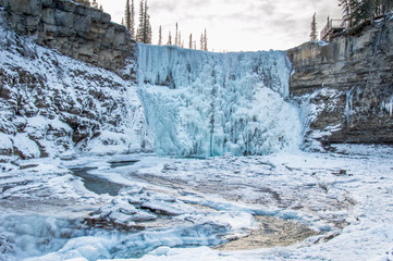 Looking towards a majestic icy frozen waterfall on a beautiful winter day in Canada