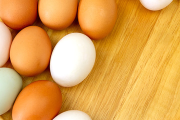 White and brown eggs on wooden background.