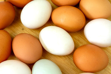 White and brown eggs on wooden background.