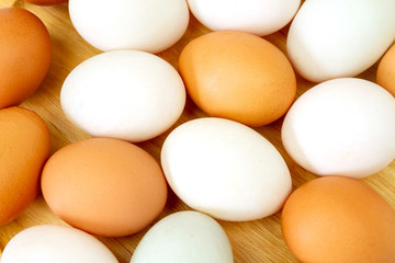 White and brown eggs on wooden background.
