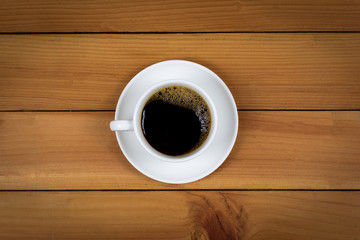 Cup of coffee on wood background, top view.