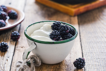 Fototapeta na wymiar Morning meal, yogurt, fresh summer blackberries in rural mug
