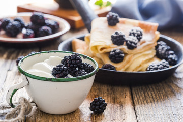 Crepes,yogurt in rural mug, fresh blackberries, healthy breakfast