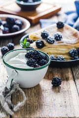 Crepes,yogurt in rural mug, fresh blackberries, healthy breakfast