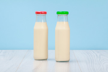 Two bottles of milk with red and green cap on blue background.
