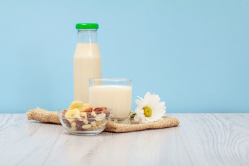 Obraz na płótnie Canvas Bottle and glass of milk, bowls with muesli on sackcloth.