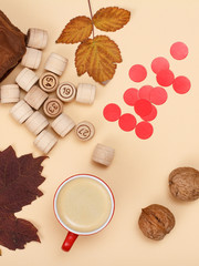 Wooden lotto barrels with brown bag and cup of coffee on beige background. Autumn theme.