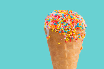 Ice cream cone close up. White ice cream scoop in a waffle cone on a blue background. Sweet dessert decorated with multicolored sprinkles