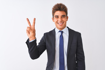 Young handsome businessman wearing suit standing over isolated white background smiling with happy face winking at the camera doing victory sign. Number two.