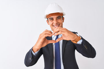 Young handsome architect man wearing suit and helmet over isolated white background smiling in love doing heart symbol shape with hands. Romantic concept.