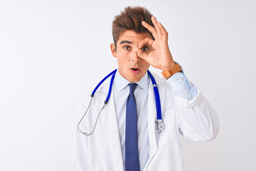 Young handsome doctor man wearing stethoscope over isolated white background doing ok gesture shocked with surprised face, eye looking through fingers. Unbelieving expression.