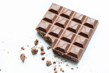 Broken piece of chocolate with crumbs on a white background. Cocoa Dessert