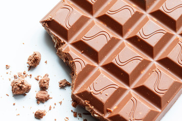 Broken piece of chocolate with crumbs on a white background. Cocoa Dessert