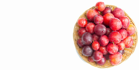 Bowl with plums on a white background top view