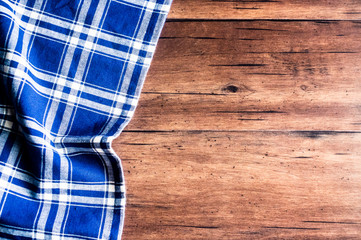 Checkered blue napkin on an old wooden brown background, top view. Image with copy space. Kitchen table with a towel - top view with copy space. 
