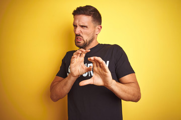 Young safeguard man wearing security uniform over yellow isolated background disgusted expression,...