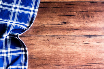 Checkered blue napkin on an old wooden brown background, top view. Image with copy space. Kitchen table with a towel - top view with copy space. 