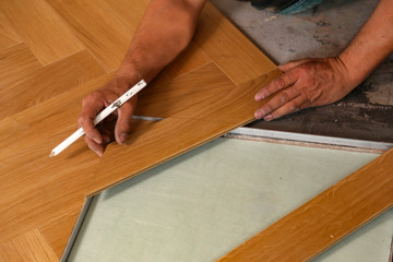 Worker laying parquet flooring. Worker installing wooden laminate flooring