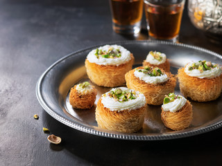 Kataifi, kadayif, kunafa, baklava pastry nest cookies with pistachios with tea. Cooking sweets turkish, or arabic traditional ramadan pastry dessert on a dark background.