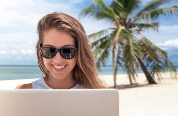 Young woman working with laptop computer on tropical island beach under palm trees Freelance  concept