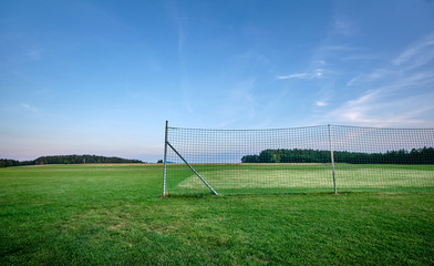 A fence standing in the middle of nowhere in an countryside landscape in summer with grass and blue sky