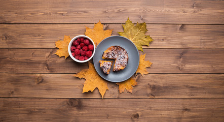 Seasonal autumn background. Frame of maple leaves and a cake over wooden background.