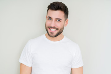 Fototapeta premium Young handsome man wearing casual white t-shirt over isolated background looking away to side with smile on face, natural expression. Laughing confident.