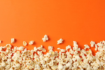 Flat lay composition with popcorn on orange background, copy space - obrazy, fototapety, plakaty