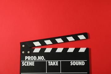 Fototapeta na wymiar Black clapperboard on red background, space for text