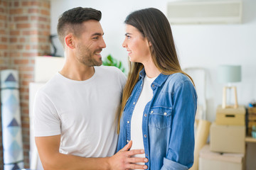 Fototapeta premium Beautiful young couple moving to a new house, smiling happy arround cardboard boxes