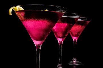 Three cosmopolitan cocktails in line on black counter