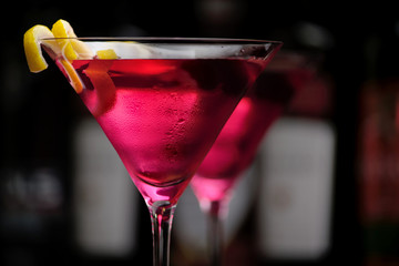 Cropped two cosmopolitan cocktails in line in club on black