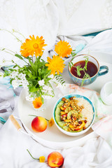 Bowl of fresh oatmeal porridge with kiwi, peach and granola